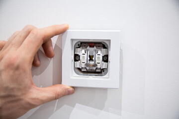 Close up of a disassembled plastic light switch and male hand. Household repairs.