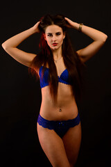 Fototapeta premium Sexy fashion brunette woman with long dark hair in blue lingerie, isolated on dark gray background