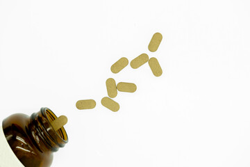 Herbal green vitamins Bacopa tablets fall out of a glass jar on a white background. Ayurveda medicine health supplements