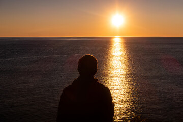 Man admiring the sunrise at Cap Bon-Ami, in the Forillon national park, Canada