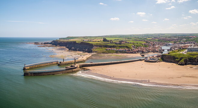 Aerial view of east and west piers each with a lighthouse and beacon, Whitby, UK.