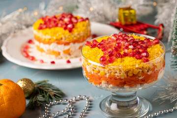 Festive New Year's salad with chicken, eggs, carrots and corn, decorated with a star of pomegranate seeds on light blue background