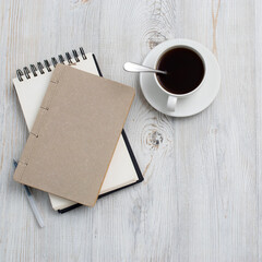 desk office with blank notepad, coffee cup and pen on wood table. Flat lay top view copy space.