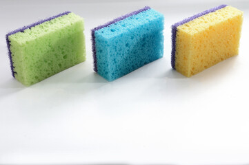 three multi-colored sponges for washing dishes on a white background.