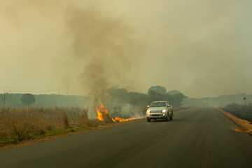 Fire and smoke on BR 163 road on Amazon during dry season and blurred car driving fast near the...