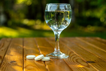 glass glass of water and instant pills on a wooden table