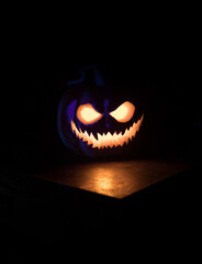 Fototapeta premium Halloween pumpkin smile and scary eyes for party night. Close up view of scary Halloween pumpkin with eyes glowing inside at black background