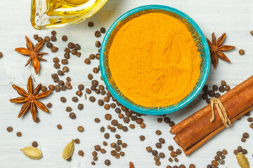 Turmeric powder close-up, black pepper peas, cinnamon sticks and anise on a light background, top view, close-up. Filled frame
