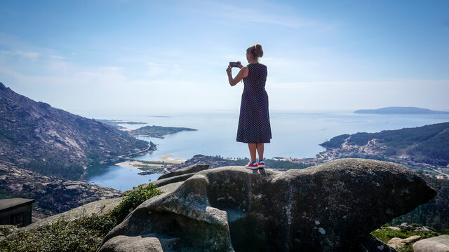 woman taking photos at the ezaro viewpoint in dumbria, la Coruña