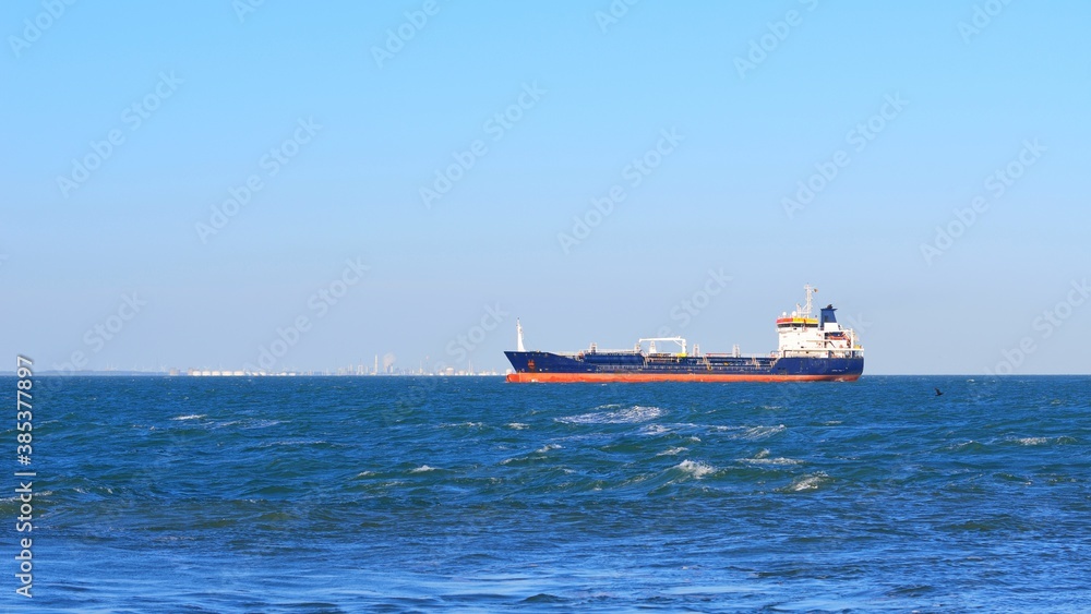 Wall mural blue cargo ship sailing near vlissingen, the netherlands. panoramic view. freight transportation, fu