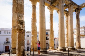 Woman photographing buildings from the Roman era of the city of Merida in Spain - obrazy, fototapety, plakaty