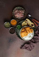 Indian Butter chicken with basmati rice, spices, naan bread. onion salad,  Brown background. Space for text