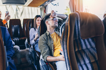 Tired young traveler yawning in the bus and listen to music through headphones. .