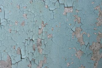 Peeling paint on the wall. Old concrete wall with cracked flaking paint. Weathered rough painted surface with patterns of cracks and peeling. High resolution texture for background and design. Closeup