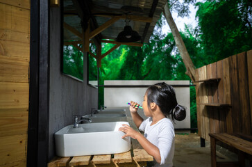 Little asian girl brushing teeth in the morning while camping