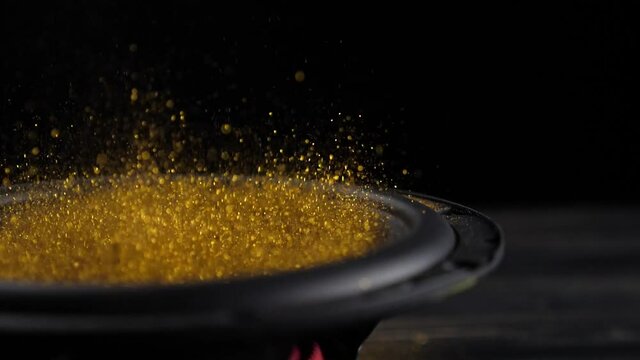 Trembling loudspeaker throwing gold flour in the air. Super slow motion close-up shot.