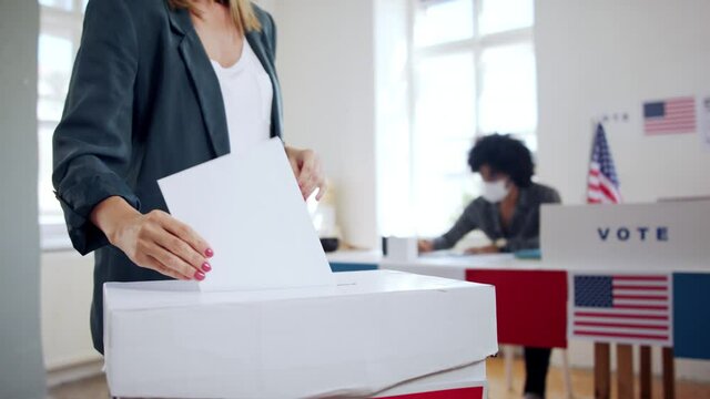 Young woman putting her vote in the ballot box, usa elections and coronavirus.