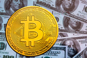Bitcoin coin against the background of us dollars. A lot of American money dollars and gold...
