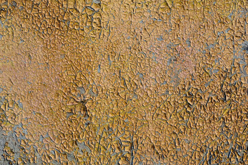 Cracked and peeling yellow paint on a wooden wall