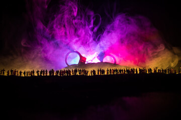 People and police government power concept. Crowd looking on big handcuffs at night with fog and backlight. Creative artwork decoration. Selective focus.