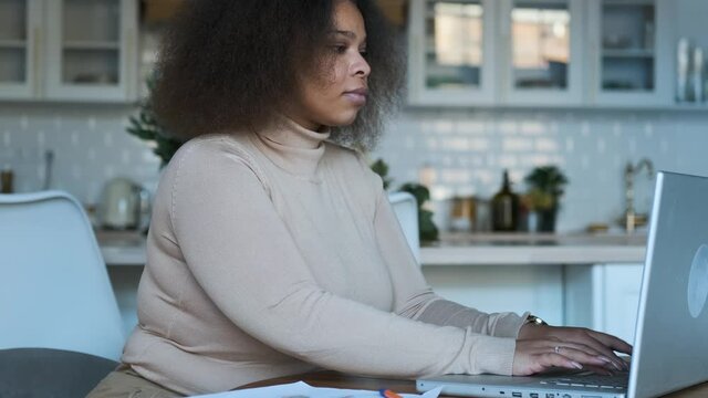 business woman making notes at the laptop while sitting at the table at home