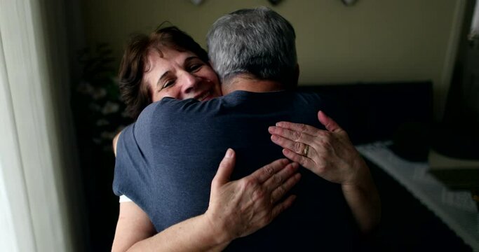 Older married couple embracing each other at home. Senior husband showing empathy and support with wife