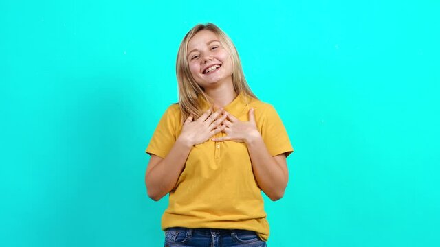 Happy young woman. Beautiful Caucasian woman in yellow T-shirt and long blond hair standing on blue background. A little fat teenager. Advertising concept.