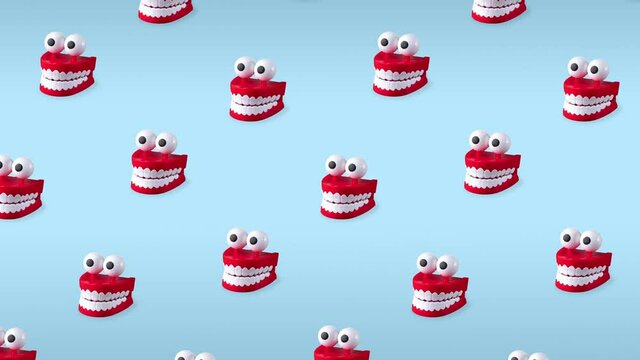 seamless looping animation of chattering teeth toys with big eyes on blue pastel background. patern of plastic red mouths with white fangs is a concept of oral hygiene and healthy teeth
