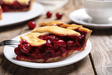 Slice of delicious fresh cherry pie on wooden table, closeup