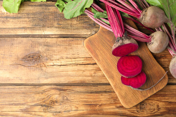 Cut and whole raw beets on wooden table, flat lay. Space for text