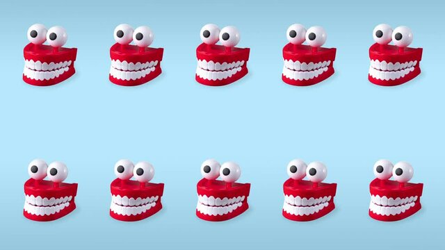 seamless looping animation of two rows chattering teeth toys with big eyes on a blue pastel background. plastic red mouths with white fangs is a concept of oral hygiene and healthy teeth, copy space