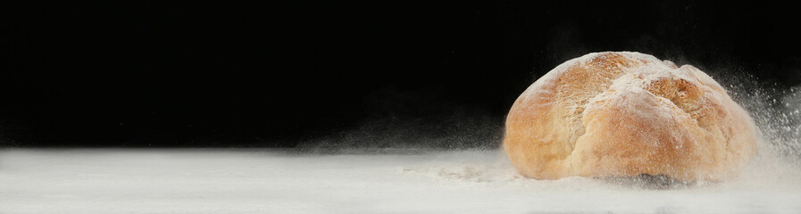Bread made from wheat dough on table against black background, space for text. Banner design