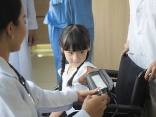 Obraz premium A patient, a girl in a wheelchair, is taking blood pressure measurements, followed by a female doctor among the encouraging doctors.