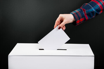 Elections and voting concept. Woman puts ballot paper in box on a black background.