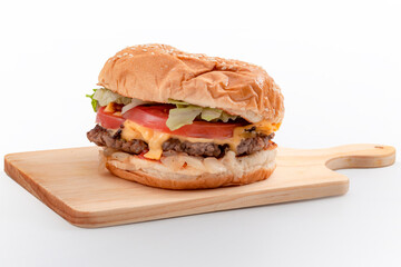 Western diet and fattening diner fast food concept with hamburger on wooden board isolated on white background with clipping path cutout