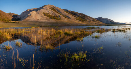 The Seaside ridge is reflected in the water. Lake Baikal coast