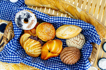 Canasta de pan con surtido, donas, conchas, bísquet, cuernito y bolillo, en toma cenital sobre...