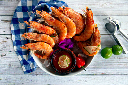 plato de camarones para pelar acompa&ntilde;ado de caldo de jaiba en toma cenital sobre madera blanca