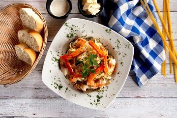 Pasta con camarón en salsa de queso mozzarella en composición cenital y mesa de madera blanca