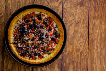 Pizza de sarten con vegetales y queso fotografiada en toma cenital sobre mesa de madera
