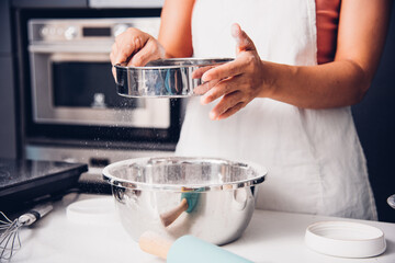 Woman girl in kitchen cooking baker bakery powder dough with baker sieve sifting