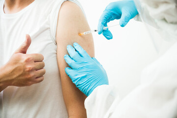 Doctor injecting vaccine covid-19 to young man. Vaccination concept.