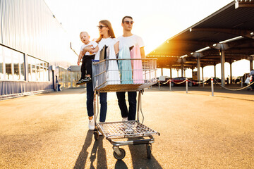Happy family with child with shopping bags and shopping trolley on background of shopping mall, family shopping