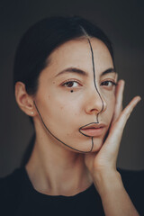 a large portrait of a dark-haired female artist with brown eyes and a black stripe across her face