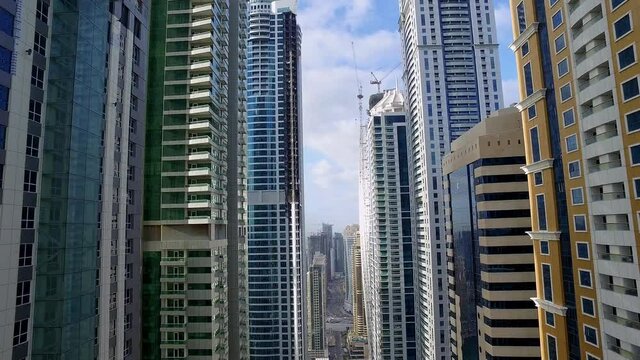 Breathtaking APV shot of the towering skyscraper of Dubai marina as the camera dolly in between building capturing an amazing view 6-axis stabilized gimbal, Shotover F1, 8K, parallax.