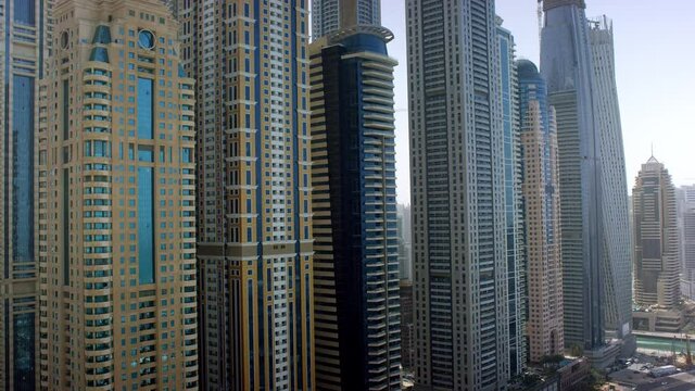 An up close view of of the towering skyscrapers at the JBR marina walk capturing an amazing details of the side of the building, Aerial, 6-axis stabilized gimbal, Shotover F1, 8K.