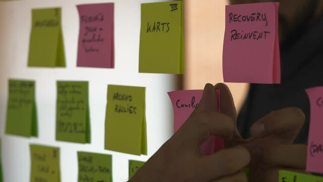 Closeup of hand sticking pink post-it note with word conclusion on glass surface