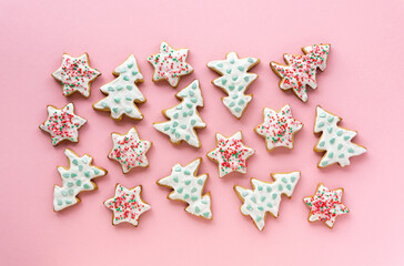 Homemade christmas gingerbread cookies in the shape of stars and trees on a pink background, top view