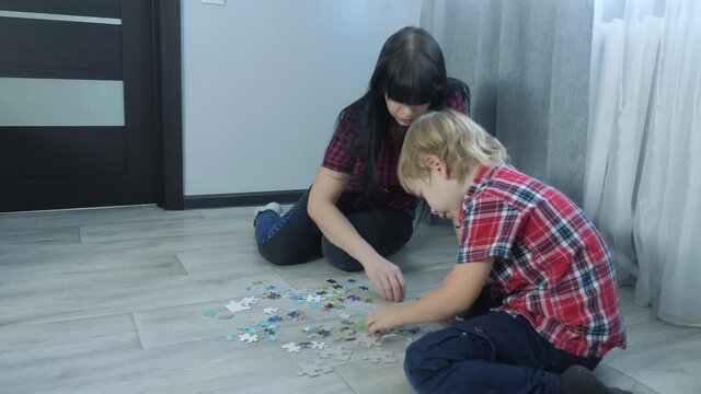 happy family collection puzzles teamwork. development of fine motor skills and lifestyle thinking. little boy a and girl mom collect mosaic puzzles