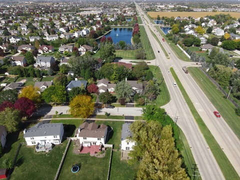 Overhead Aerial View Of Colorful Autumn Trees Residential Houses And Yards Along Suburban Street In Chicago Area. Midwest USA